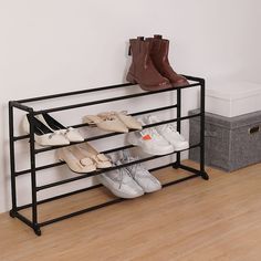 several pairs of shoes are lined up on a black shoe rack in front of a white wall