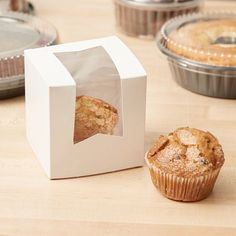 a muffin in a paper bag next to a cupcake