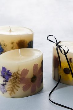 three candles with flowers painted on them sitting next to each other