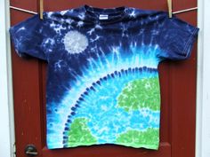 a tie - dyed shirt hanging on a door with the earth in it's center