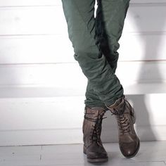 a person standing on top of a wooden floor wearing boots and holding a cell phone