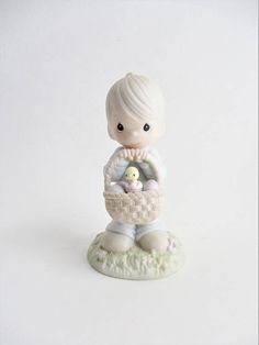 a figurine of a boy holding a basket with a baby duck in it