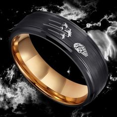 a black and gold wedding band with two dragon symbols on the inside, in front of clouds