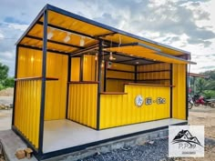 a yellow and black building sitting on the side of a dirt road next to a forest