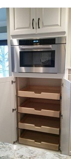 a microwave oven built into the side of a kitchen cabinet with pull out drawers on both sides