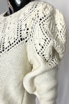 the back of a white sweater with crochet on it and a pair of scissors