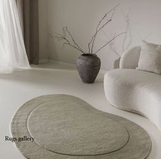 a white living room with two round rugs on the floor and a potted plant