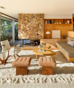 a living room filled with furniture and a fire place in the middle of a floor to ceiling window