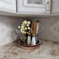 kitchen utensils are arranged in a tray on the counter top, with white flowers