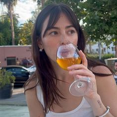 a woman drinking from a wine glass outside