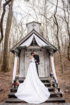 a woman in a wedding dress is standing on steps near a gazebo and trees