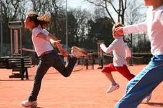 three young children playing tennis on a court