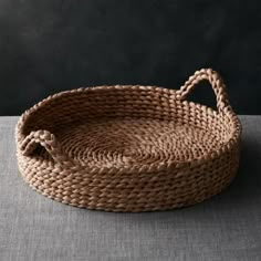 a woven basket sitting on top of a gray tablecloth covered floor next to a black wall