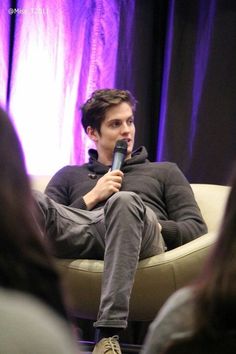 a man sitting in a chair holding a microphone