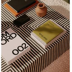 the table is covered with black and white striped papers, books, and a vase