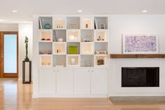 a living room filled with lots of white furniture next to a fire place under a painting