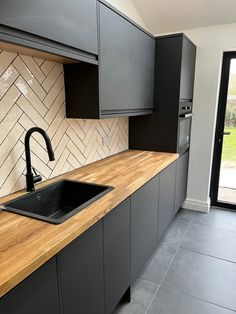 a kitchen with black cabinets and wooden counter tops