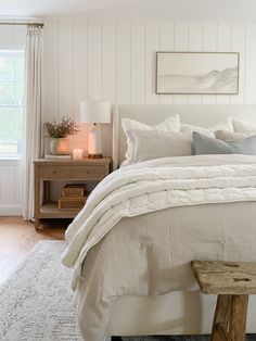 a bed with white linens and pillows in a bedroom next to a wooden bench