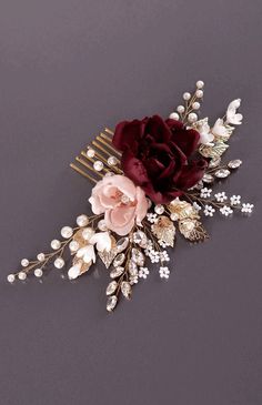 a hair comb with flowers and pearls on it's side, against a gray background