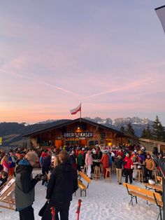 a group of people standing in the snow near some skis and chairs with flags on them