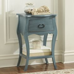 a blue table with a drawer and pillow on it next to a white rug in front of a door