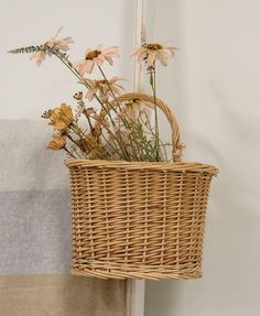 a wicker basket with flowers in it hanging on the wall next to a towel