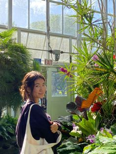 a woman is standing in front of some plants