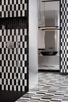 a bathroom with black and white tiles on the floor, shower head, and mirror