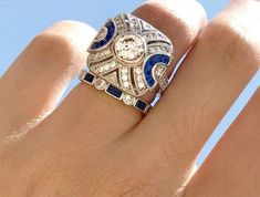 a woman's hand with a diamond and blue sapphire ring on top of it