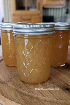 three jars filled with honey sitting on top of a wooden table