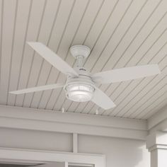 a white ceiling fan mounted on the side of a wall next to a door and window