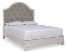 an upholstered bed with white linens and buttons on the headboard is shown