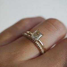 a woman's hand with a diamond ring on top of her finger and an engagement band