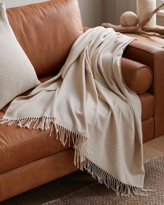 a brown leather couch with a blanket on it