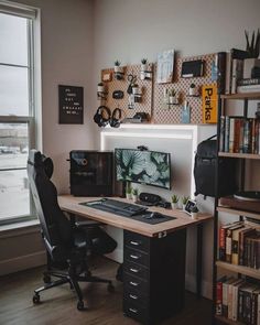 a desk with a computer monitor and keyboard on top of it in front of a window