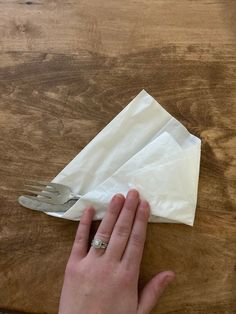 a person holding a fork and napkin on top of a wooden table