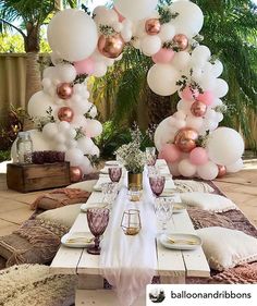 a table set up for a party with pink and white balloons