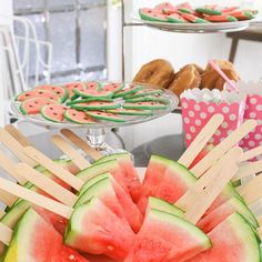 watermelon slices and popsicle sticks are arranged on a platter in front of pastries