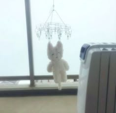 a stuffed animal hanging from the side of a window next to a piece of luggage