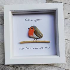 a small bird sitting on top of a wooden stick in a white box frame with words above it