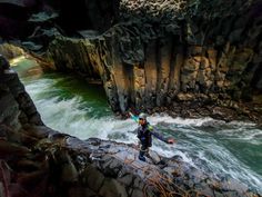 a man standing on the edge of a cliff next to a body of water with rapids