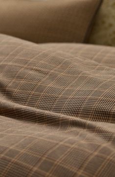 a close up view of a bed with brown and tan plaid sheets, pillows and pillow cases