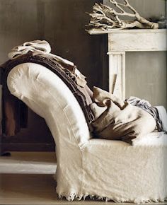 a white couch sitting in front of a fireplace with pillows and blankets on top of it