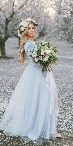 a woman in a blue dress holding a bouquet and wearing a flower crown on her head