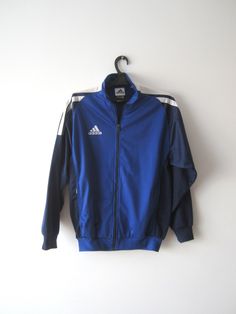 "Vintage Blue Adidas Jacket Blue Adidas Zipper Running Jacket Unisex Jogging Parka Blue Soccer Jacket Three Stripes Size Large Adidas Cardigan Label size: D 176; GB 34/36; F 16A Measurements: (lying flat) Length - 28.5\"/ 72.5 cm Shoulders: 20\"/ 51 cm Pit to pit: 22.5\"/ 57 cm Waist: 19.5\"/ 49.5 cm Sleeve: 22.5\"/ 57 cm Please check measurements to insure a proper fit. Remember to allow yourself some extra room for movement. You can compare these with something from your closet that fits you w Sporty Blue Windbreaker With Zipper Closure, Blue Sports Track Jacket With Zipper Closure, Winter Blue Windbreaker With Zipper Closure, Casual Blue Windbreaker With Zipper, Casual Blue Windbreaker With Zipper Closure, Blue Long Sleeve Outerwear With Zipper Closure, Blue Long Sleeve Outerwear With Zipper, Blue Sportswear Windbreaker With Pockets, Blue Sports Outerwear With Zipper Closure