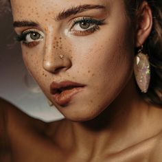 a woman with freckles on her face is posing for the camera while wearing earrings