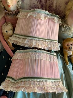 two stuffed animals sitting on top of a bed next to a pink lamp shade and teddy bear