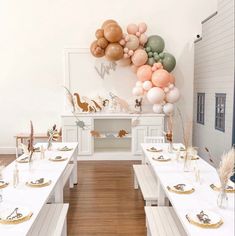 a room filled with tables covered in white tablecloths and balloons hanging from the ceiling