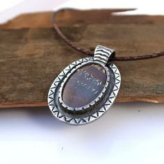 Handmade .999 fine silver necklace with an Australian boulder opal cabochon. Pendant measures  3.5cm wide by 5.8cm long.  Pendant including stone weighs 44 grams. Includes gift box. I offer a few different cord lengths. The cord is 3mm round braided leather with sterling silver tube ends and clasp.  Handmade by Mike Summers. We are husband and wife Mike and Annie, making silver jewelry in two uniquely different styles. With a passion for rocks and gemstones, we also cut and polish our own cabochons to use in our creations. We live and work in a tiny cabin in a remote part of Talkeetna in Alaska and it's always a bit of an adventure crossing our creek in a boat to get on the roads to the post office. We have set our dispatch time to 1-2 weeks, and we usually make a visit to the post office Boulder Opal Necklace, Australian Boulder Opal, Leather Corded Necklace, Cabochon Pendant, Silver Jewelry Handmade, Cat Necklace, Long Pendant, Husband And Wife, Boulder Opal