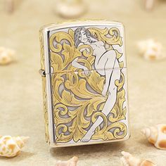 a gold and silver lighter sitting on top of a table next to sea shell shells